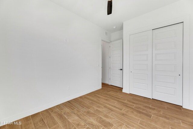 unfurnished bedroom featuring a closet, ceiling fan, and light wood-type flooring