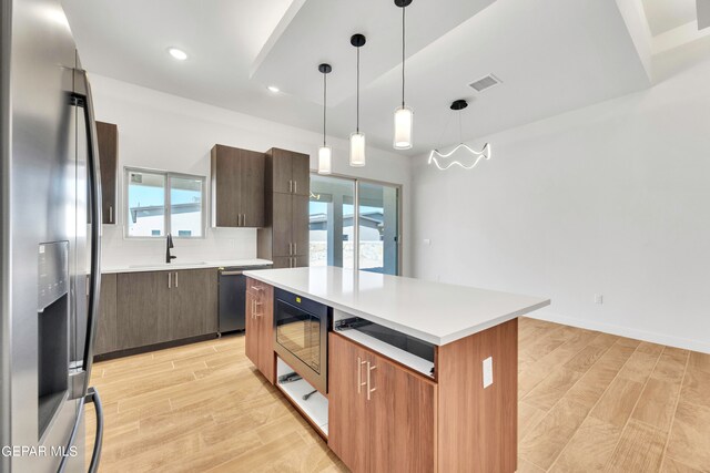 kitchen with a wealth of natural light, a kitchen island, appliances with stainless steel finishes, and light hardwood / wood-style flooring