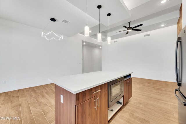 kitchen with a center island, light hardwood / wood-style floors, decorative light fixtures, stainless steel refrigerator, and black microwave