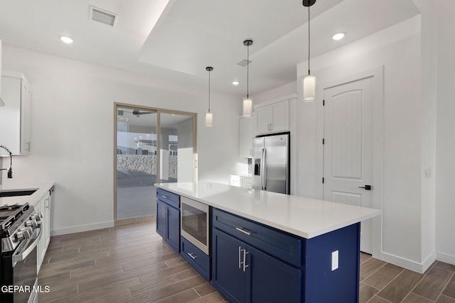 kitchen featuring dark hardwood / wood-style flooring, stainless steel appliances, pendant lighting, white cabinets, and blue cabinetry