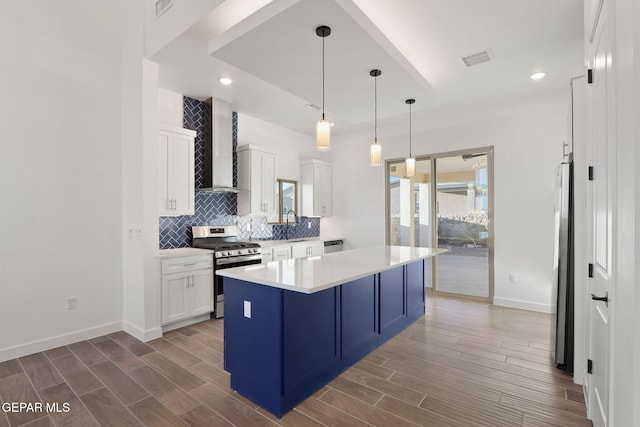 kitchen featuring a kitchen island, dark hardwood / wood-style flooring, white cabinetry, wall chimney exhaust hood, and stainless steel appliances