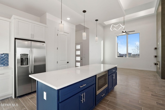 kitchen with white cabinets, hardwood / wood-style floors, backsplash, stainless steel appliances, and blue cabinets