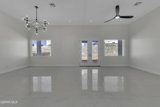 spare room featuring ceiling fan with notable chandelier and french doors