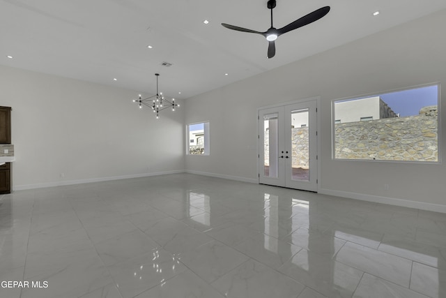 unfurnished living room with ceiling fan with notable chandelier and french doors