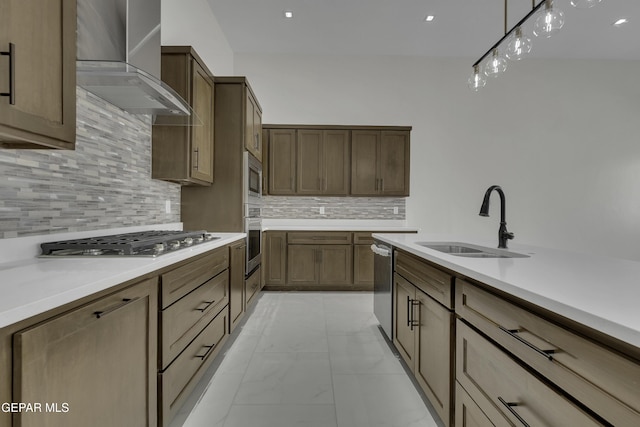 kitchen featuring hanging light fixtures, sink, appliances with stainless steel finishes, wall chimney range hood, and decorative backsplash