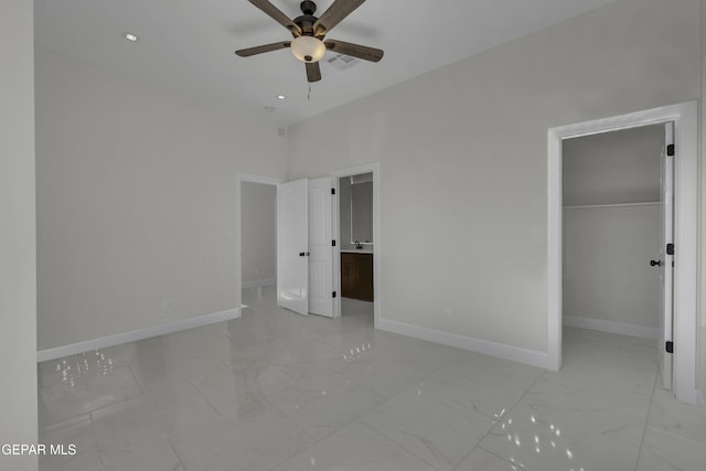 unfurnished bedroom featuring ceiling fan, a closet, ensuite bath, and a spacious closet