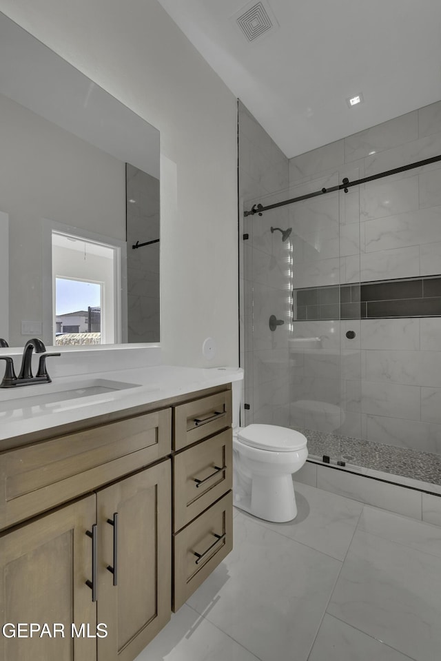 bathroom featuring toilet, vanity, and a shower with shower door