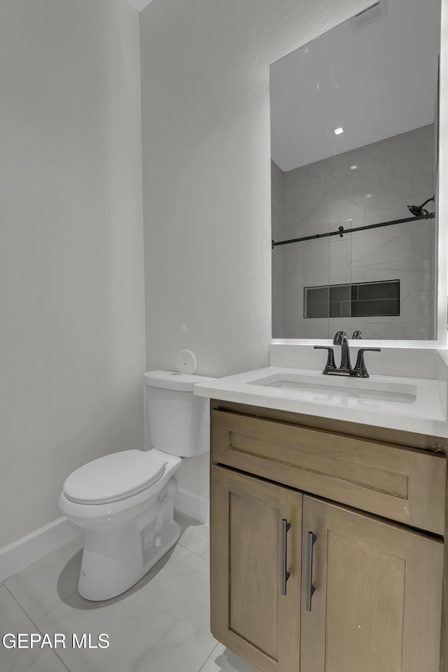 bathroom with toilet, a tile shower, and vanity