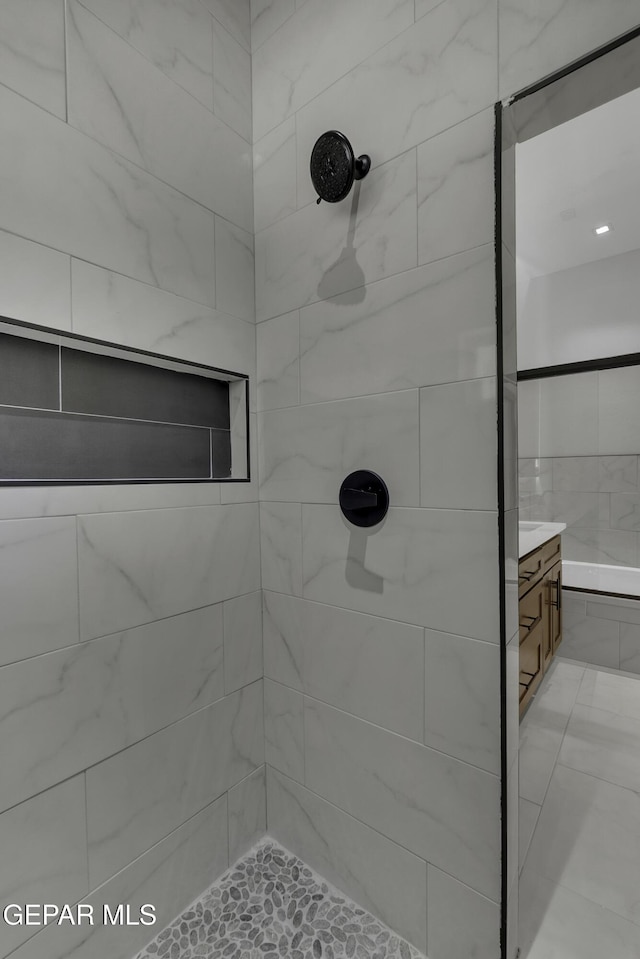 bathroom with a tile shower and vanity