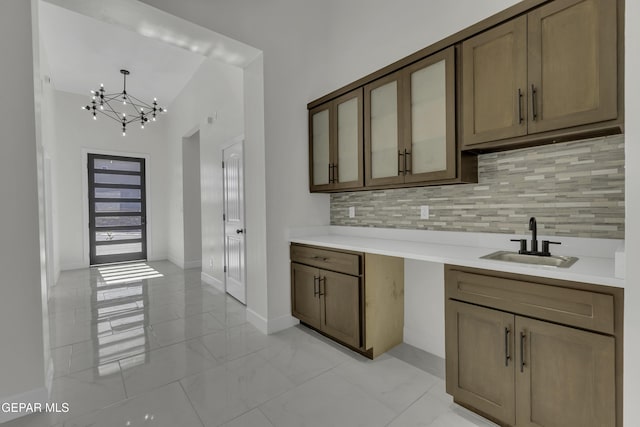 kitchen featuring sink, an inviting chandelier, decorative backsplash, and pendant lighting