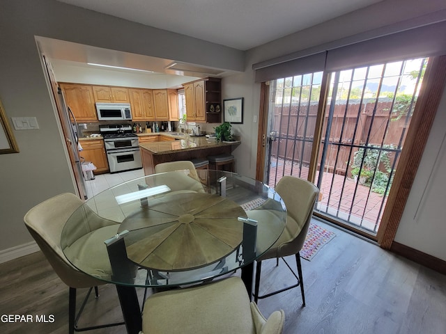 dining room with a healthy amount of sunlight, sink, and light wood-type flooring