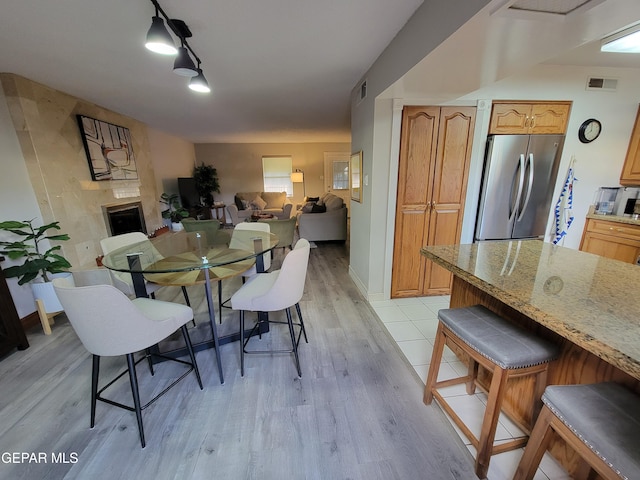 dining area featuring light hardwood / wood-style floors, track lighting, and a fireplace