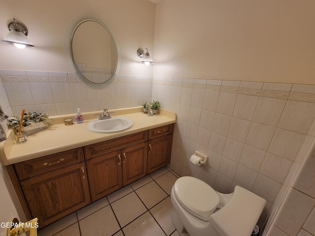 bathroom with vanity, toilet, tile patterned floors, and tile walls