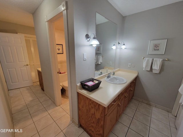 bathroom with toilet, vanity, and tile patterned flooring