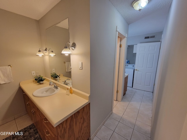 bathroom featuring washer / dryer, vanity, a textured ceiling, and tile patterned flooring