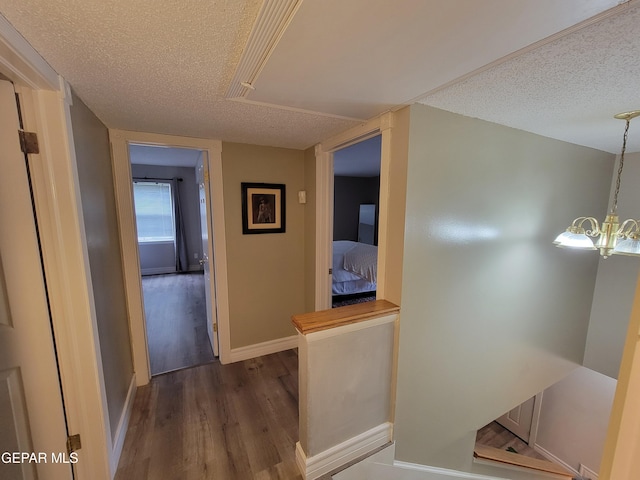 hallway featuring a notable chandelier, dark hardwood / wood-style floors, and a textured ceiling