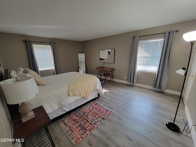 bedroom featuring a textured ceiling, multiple windows, and light hardwood / wood-style floors