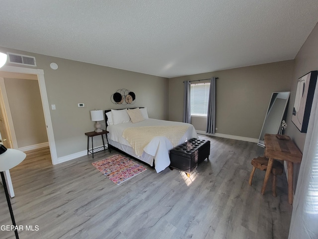 bedroom with a textured ceiling and wood-type flooring