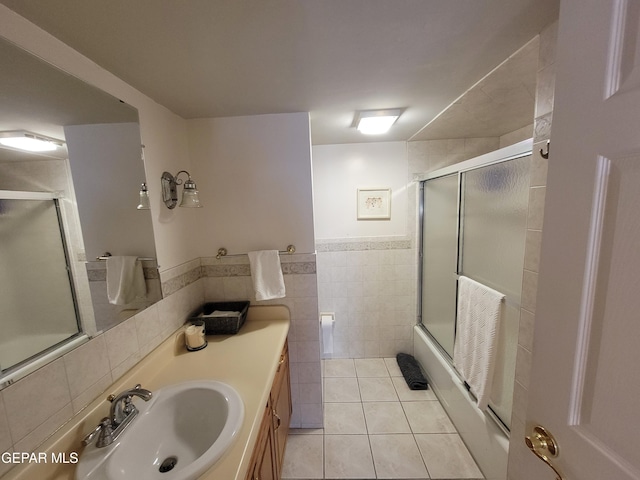 bathroom featuring tile walls, vanity, enclosed tub / shower combo, and tile patterned floors