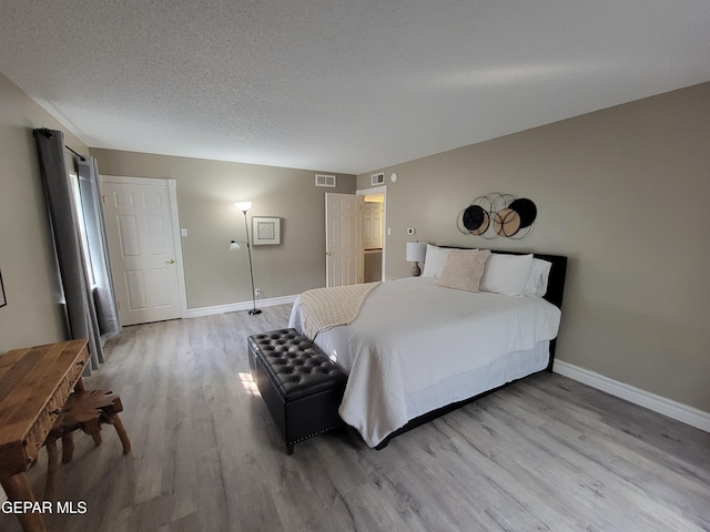 bedroom with a textured ceiling and light wood-type flooring