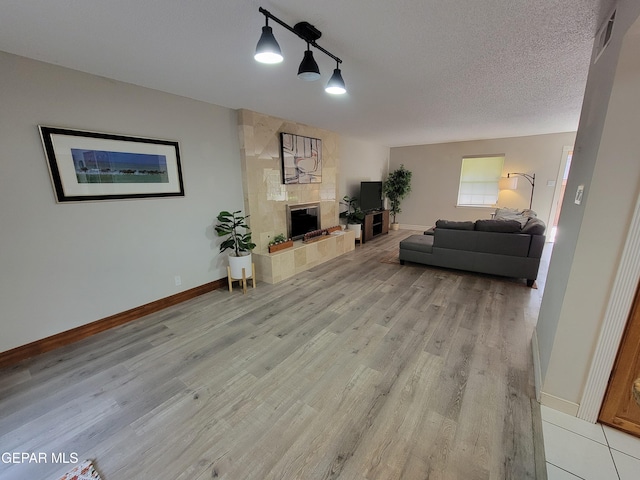 living room with a fireplace, a textured ceiling, and light wood-type flooring