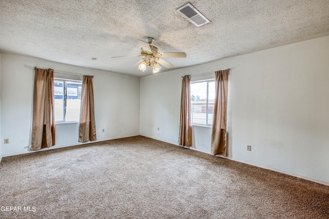 carpeted empty room with ceiling fan, a healthy amount of sunlight, and a textured ceiling