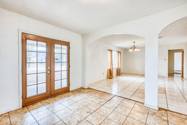 tiled empty room featuring a wealth of natural light, french doors, and a textured ceiling