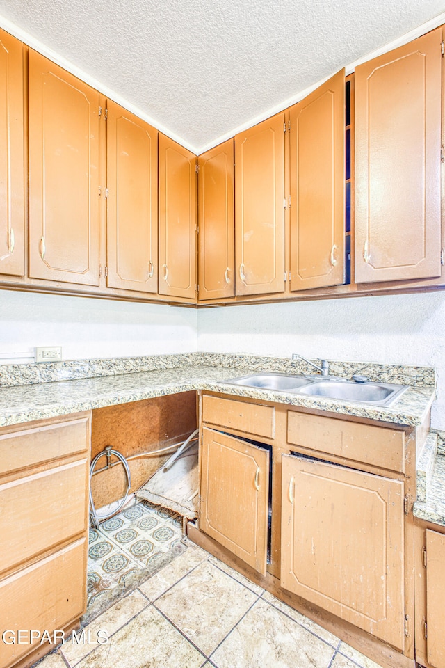 kitchen featuring a textured ceiling, sink, and light tile patterned floors