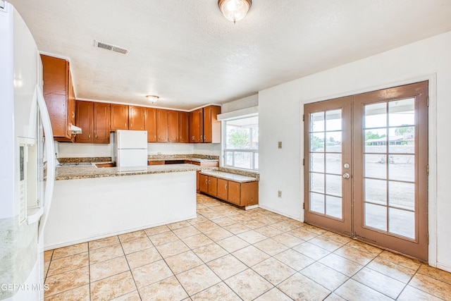 kitchen featuring french doors, white fridge with ice dispenser, a textured ceiling, and white refrigerator