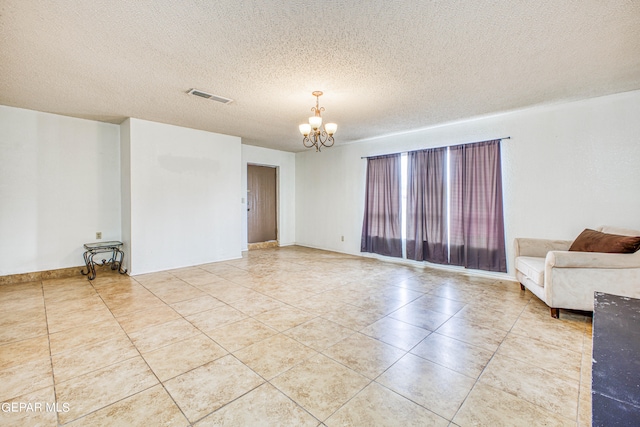 empty room with a notable chandelier, a textured ceiling, and light tile patterned floors