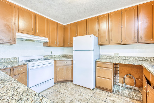 kitchen featuring white appliances, light stone counters, a textured ceiling, and light tile patterned flooring