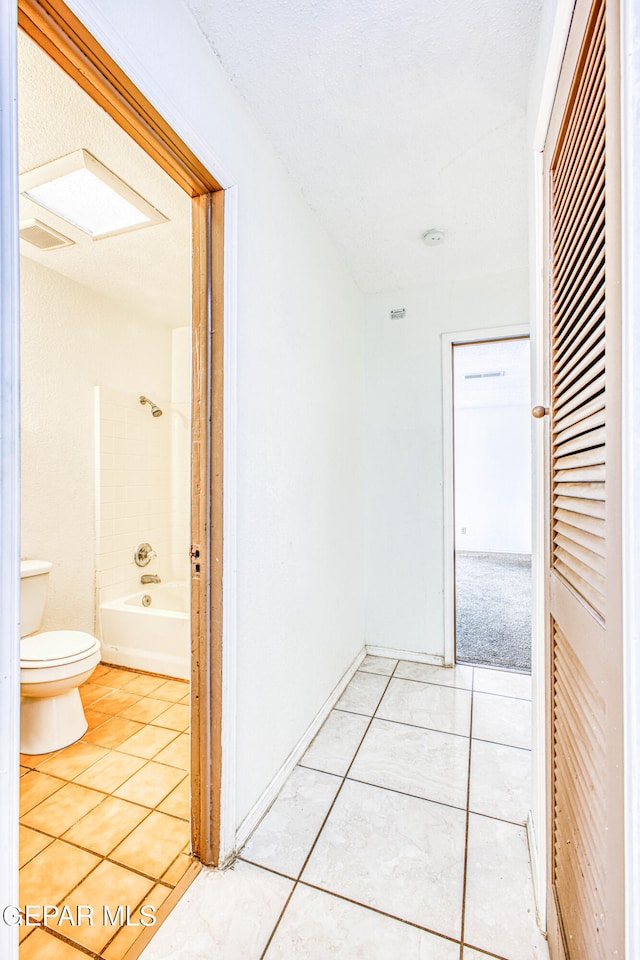 hall featuring a textured ceiling and light tile patterned floors