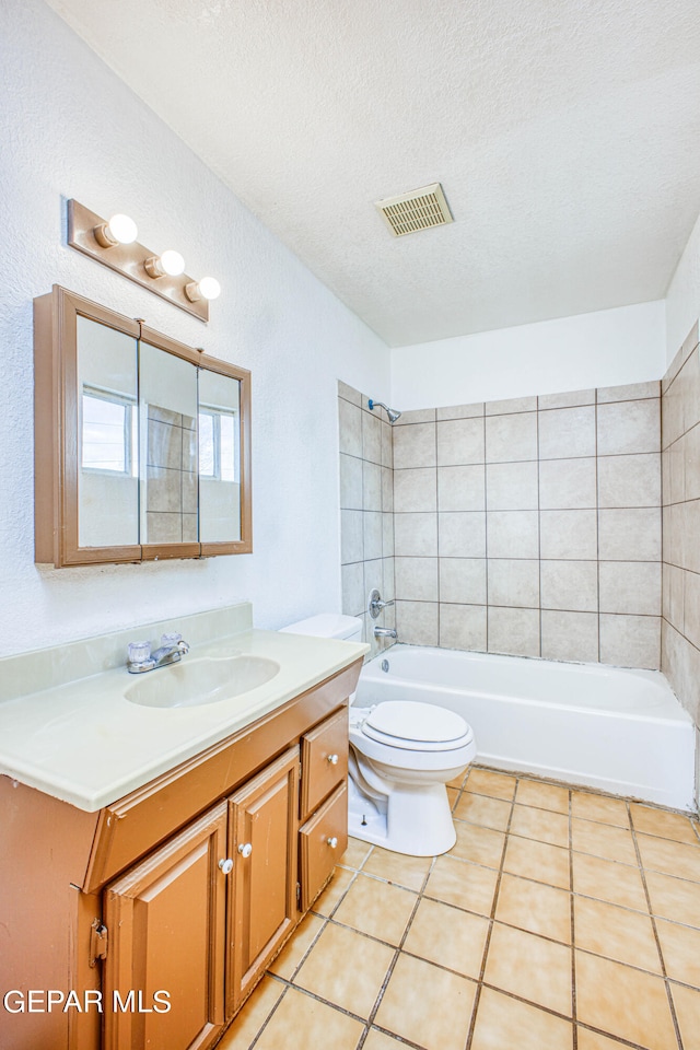 full bathroom with a textured ceiling, toilet, tile patterned floors, tiled shower / bath, and vanity