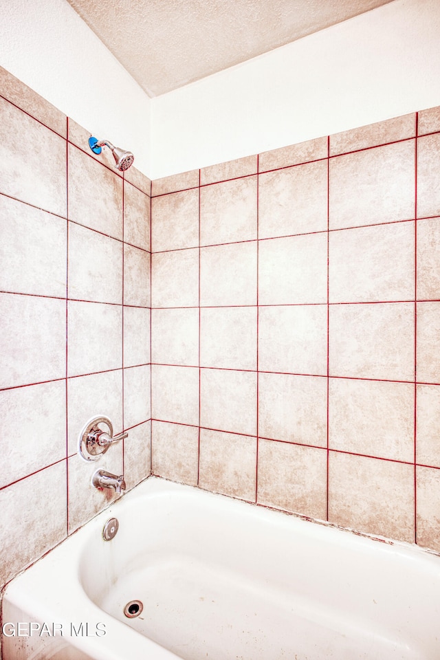 bathroom featuring tiled shower / bath combo and a textured ceiling