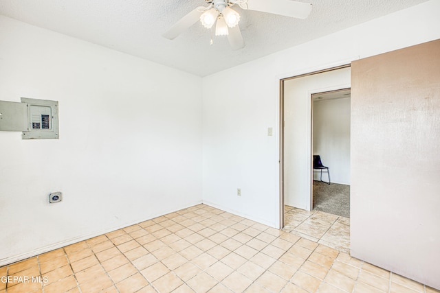 tiled spare room featuring electric panel, a textured ceiling, and ceiling fan