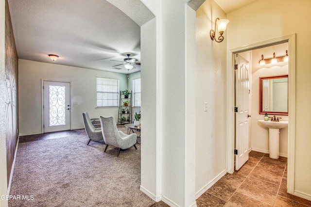 hall featuring sink, carpet, and a textured ceiling