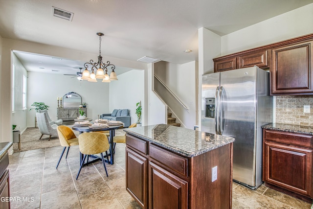 kitchen with backsplash, dark stone counters, stainless steel fridge with ice dispenser, a kitchen island, and hanging light fixtures