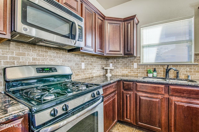 kitchen featuring appliances with stainless steel finishes, tasteful backsplash, dark stone countertops, and sink