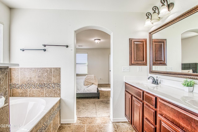 bathroom featuring tile patterned flooring, vanity, and a relaxing tiled tub