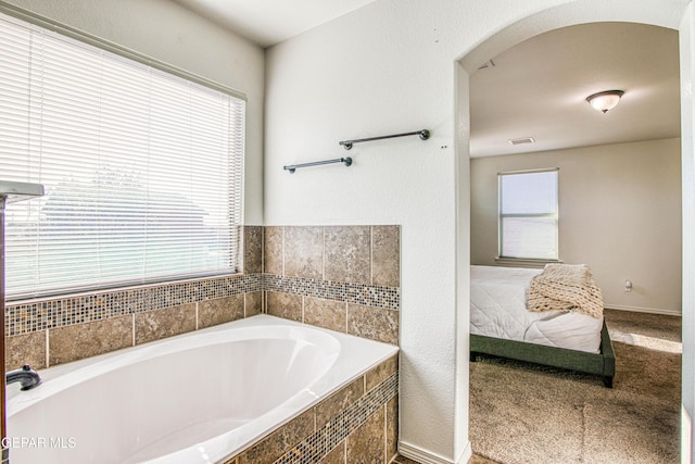 bathroom with a relaxing tiled tub