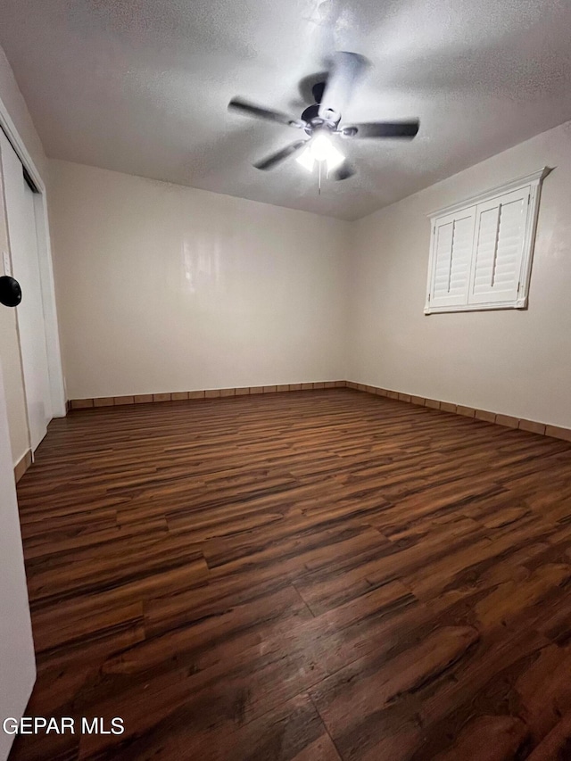 unfurnished room with dark wood-type flooring, a textured ceiling, and ceiling fan