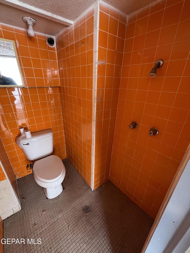 bathroom with tile patterned flooring, tiled shower, and toilet