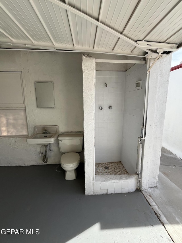 bathroom featuring sink, concrete flooring, toilet, and tiled shower