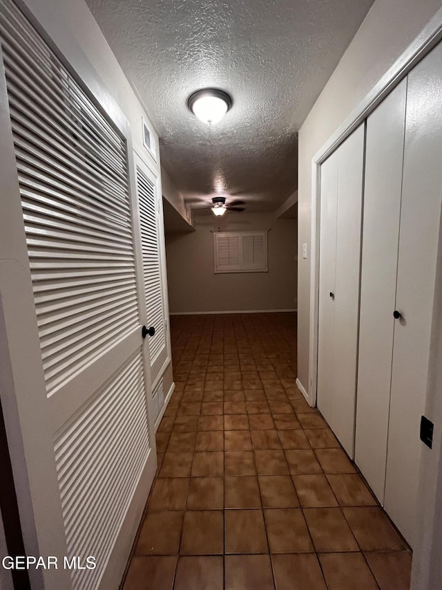 corridor featuring dark tile patterned flooring and a textured ceiling