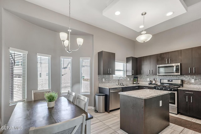 14805 Sam Garcia Ave, El Paso, TX 79938 - kitchen featuring stainless steel appliances, a towering ceiling, tasteful backsplash, dark brown cabinets, and decorative light fixtures