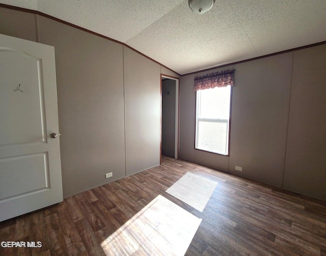 spare room featuring a textured ceiling, hardwood / wood-style flooring, and vaulted ceiling