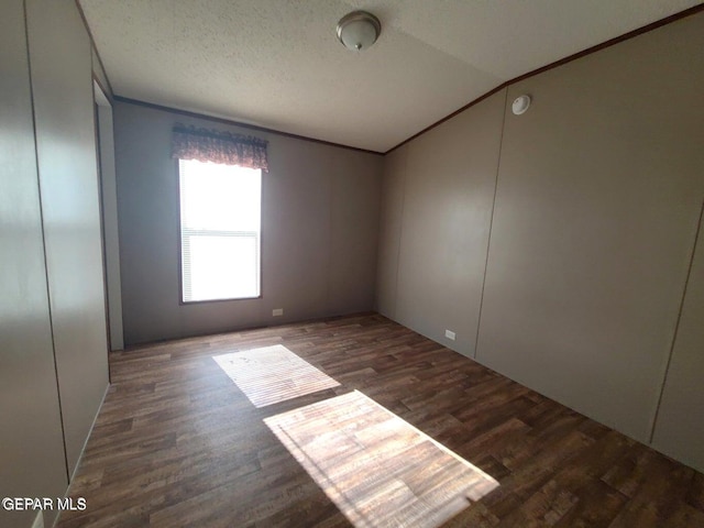 empty room with a textured ceiling, vaulted ceiling, and dark hardwood / wood-style flooring