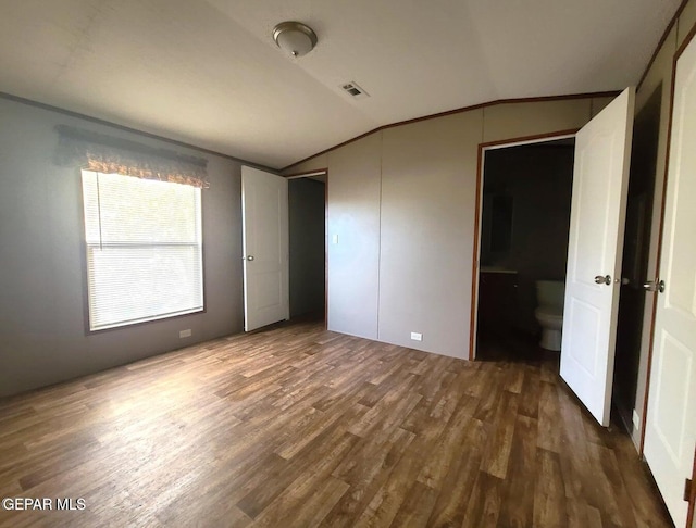 unfurnished bedroom featuring vaulted ceiling, wood finished floors, and visible vents