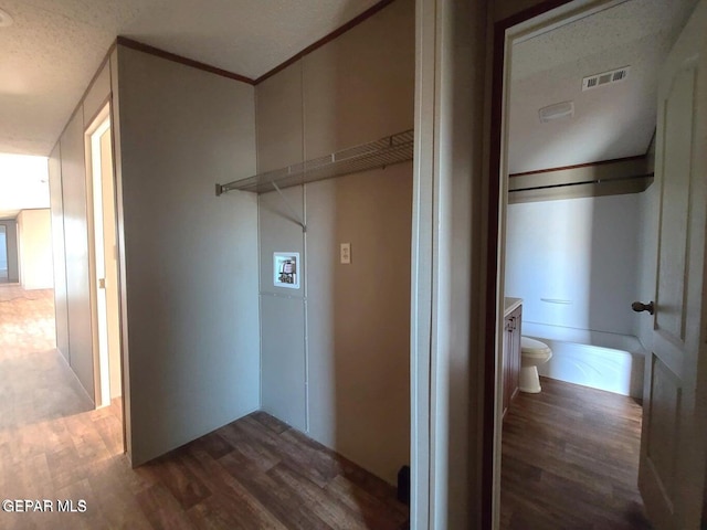 washroom featuring dark wood-type flooring, washer hookup, crown molding, and a textured ceiling