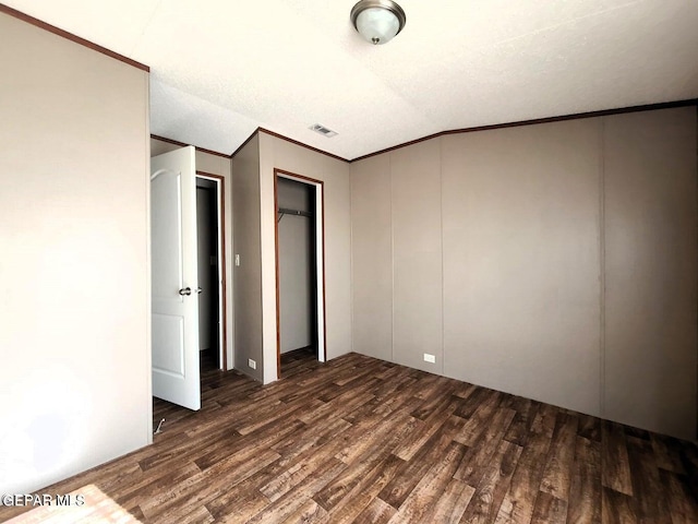 unfurnished bedroom with ornamental molding, vaulted ceiling, and dark hardwood / wood-style floors